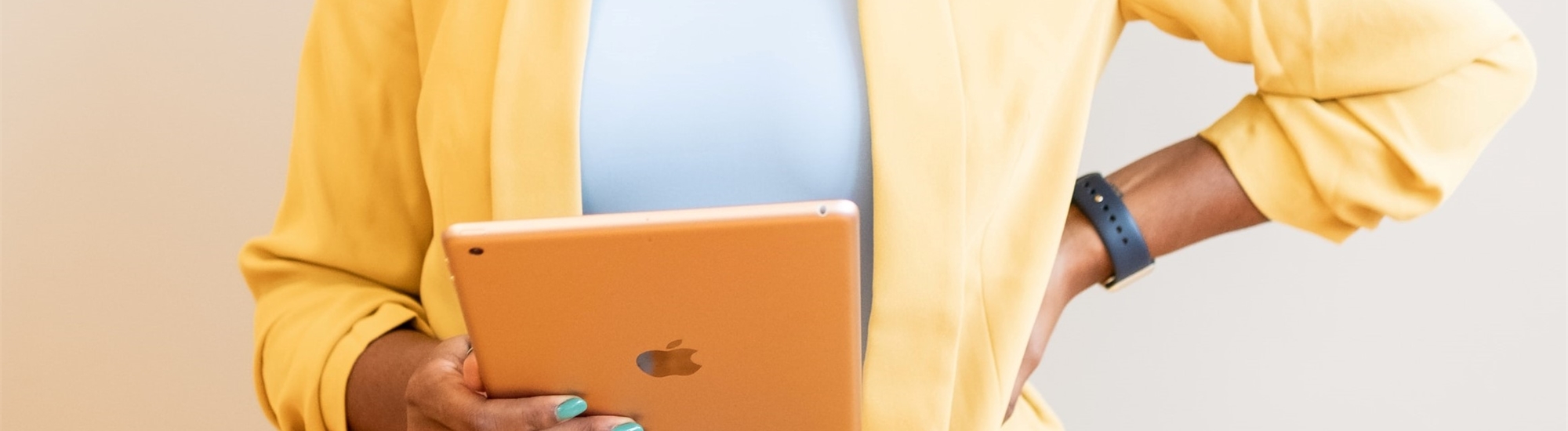 A person holding an iPad wearing a yellow jacket