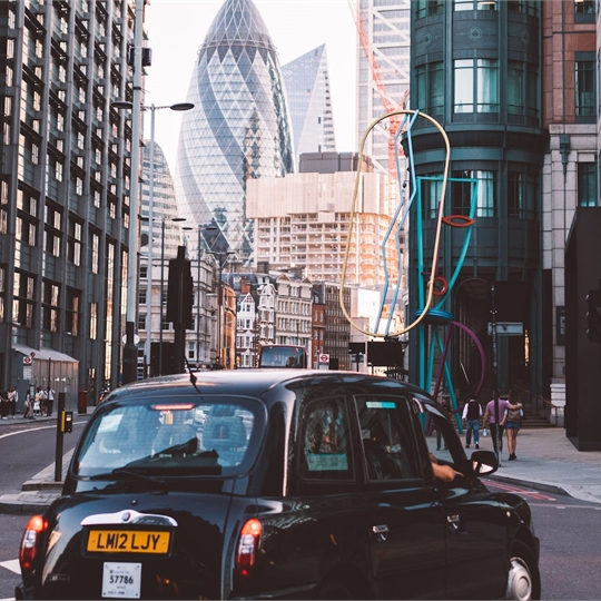 A taxi going through a street within the City of London.
