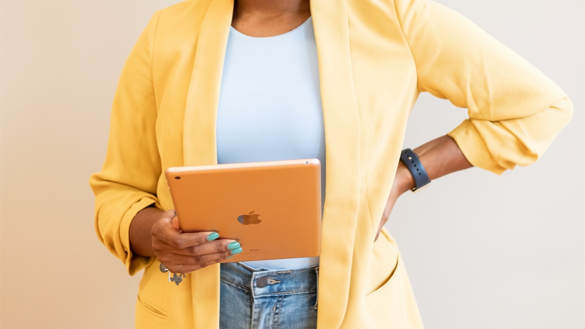 A person holding an iPad wearing a yellow jacket