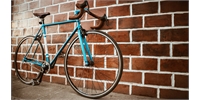 a blue road bike against a brick wall